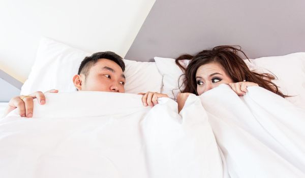A couple in bed looking at each other after sex