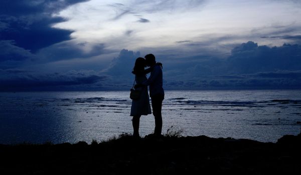 A man kissing a girl's forehead near at a beach