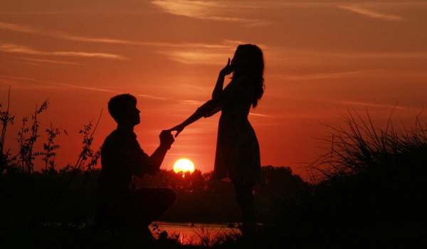 A man proposing a girl in a beautiful sunset in the background